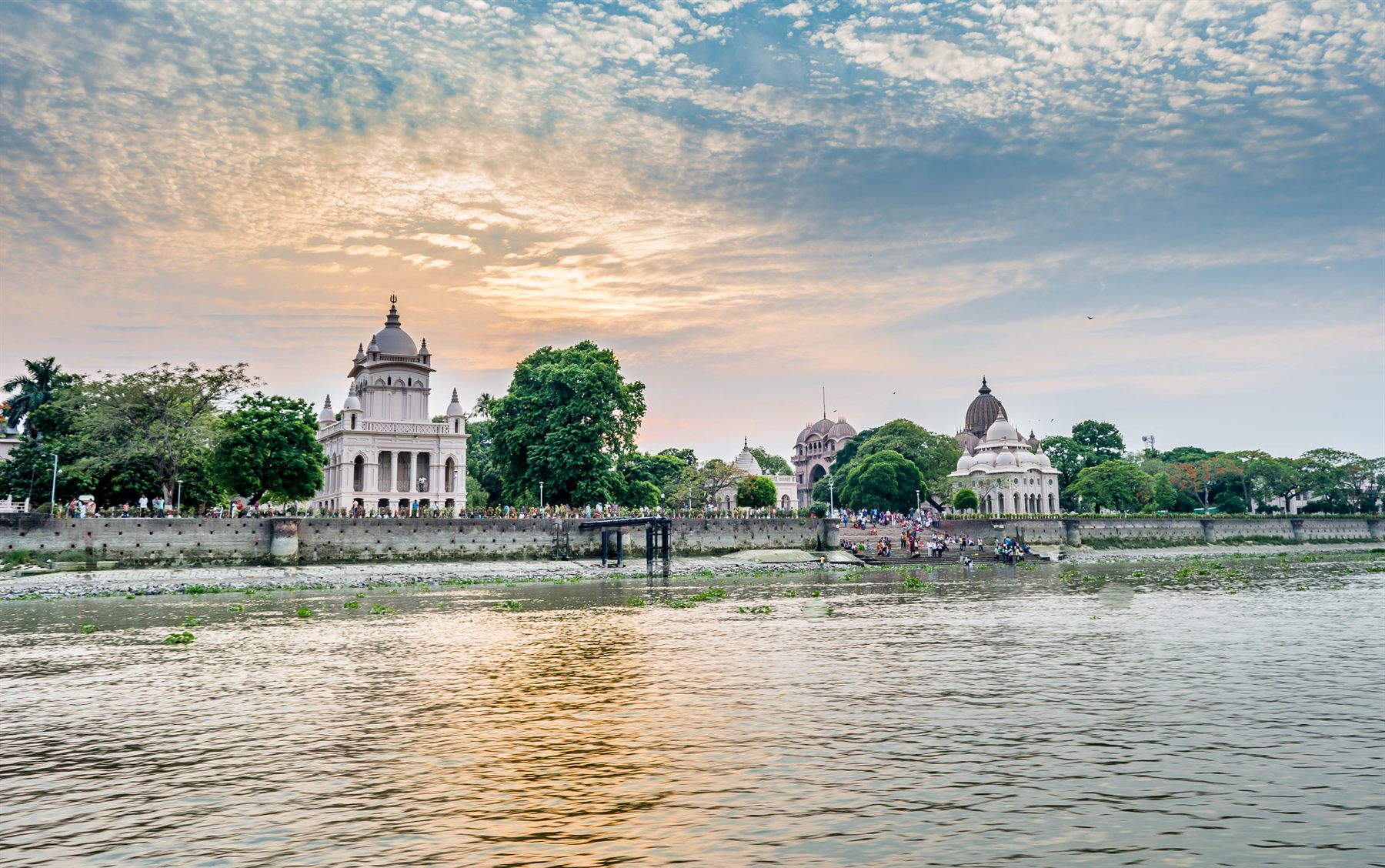 White domed temples of Belur Math on the riverbank at sunset